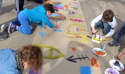 Image d'enfants peignant au sol une grande fresque